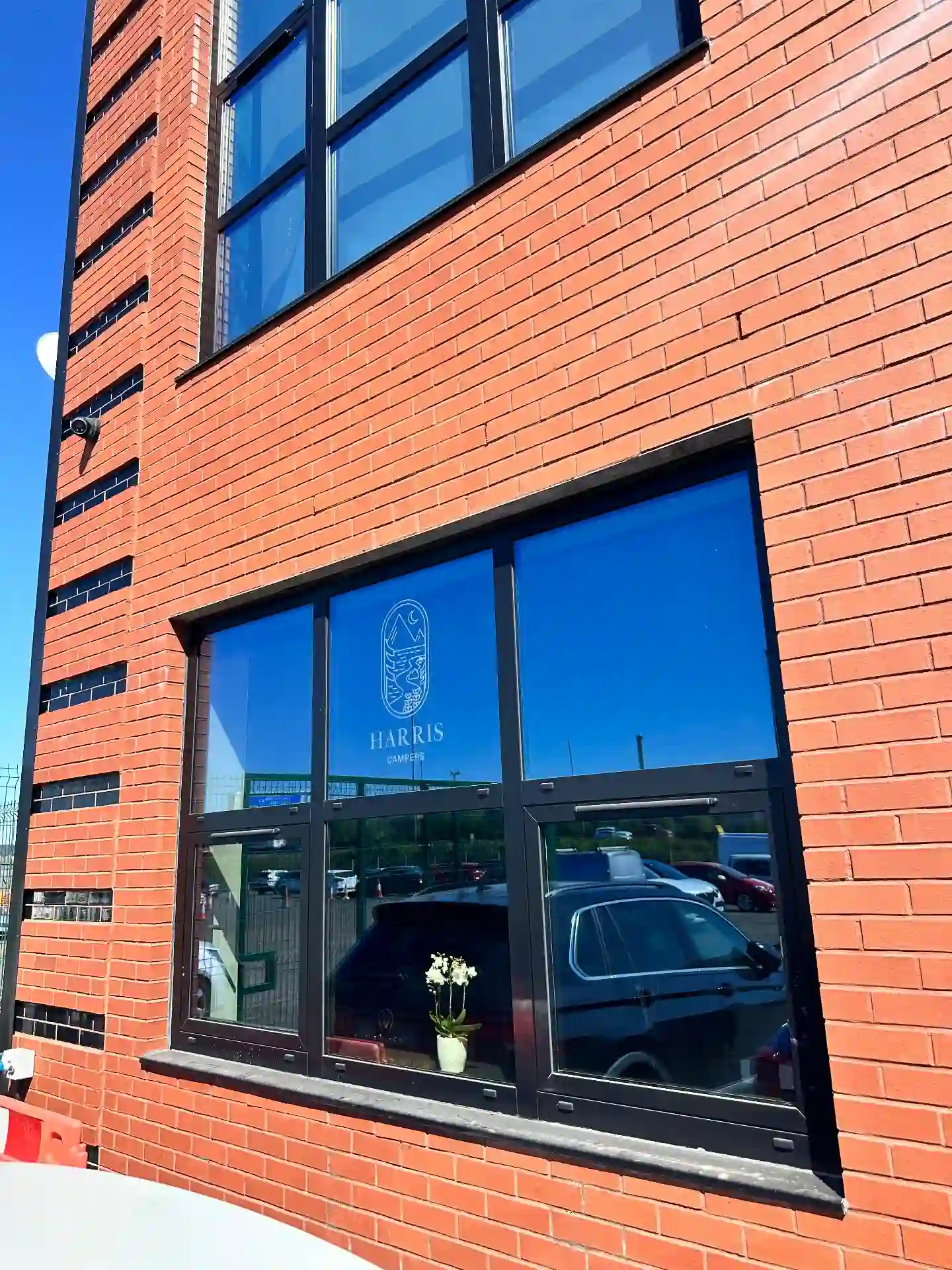Harris Campers premises with cut vinyl window graphics on the ground-floor glazing of a brick commercial unit