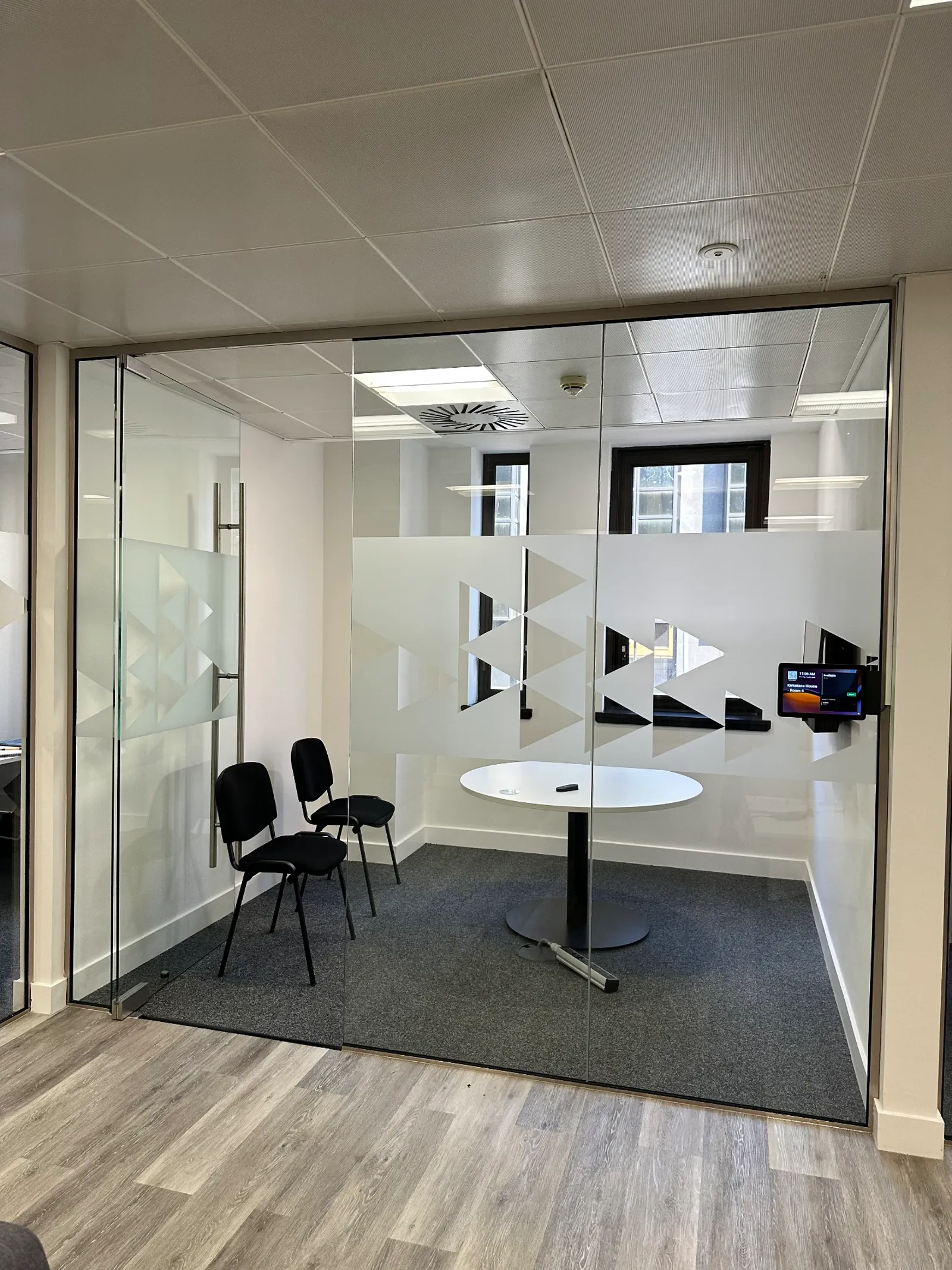 Glass meeting booth with large-scale triangle frost pattern providing privacy while keeping daylight