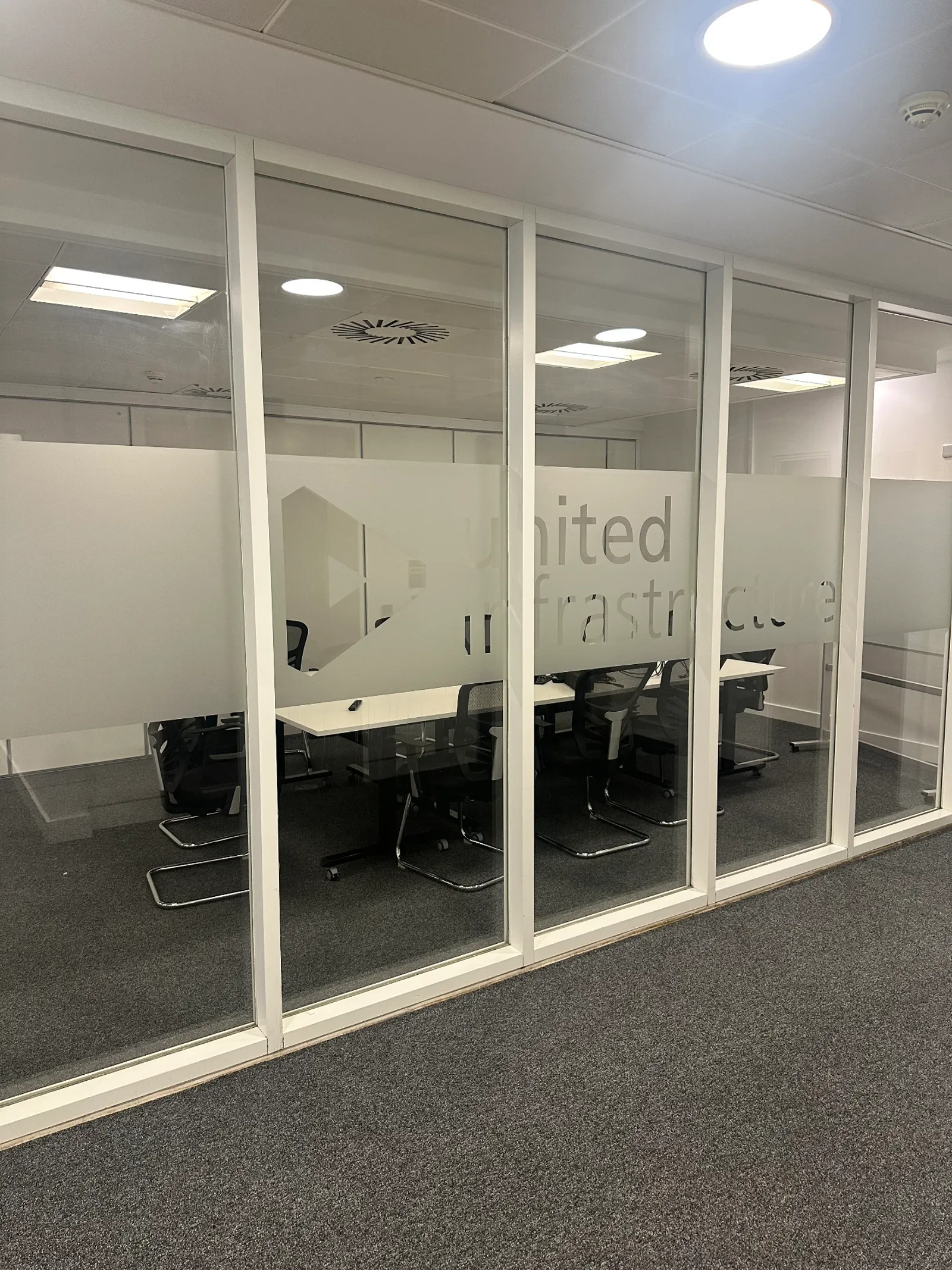 Cut-and-frost logo manifestations, patterned privacy frost to partitions, entrance door graphics — United Infrastructure, commercial signage by L4 Signs Glasgow